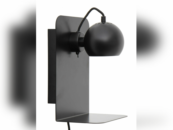 En moderne sort væghængt lampe med en afrundet, justerbar skærm og en flad, nedre hylde på en hvid baggrund.