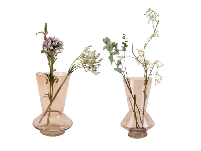 To lysebrune glasvaser med hver et par stilke af sarte hvide og lilla blomster med grønt løv står side om side på en hvid baggrund.