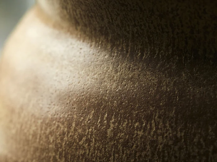 Nærbillede af en struktureret, brun keramikoverflade med pletter og subtile skygger, muligvis en del af en keramikvase eller -skulptur.