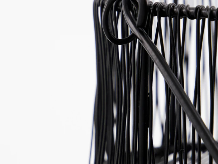 Nærbillede af sorte metaltråde, der danner et abstrakt geometrisk mønster mod en hvid baggrund.