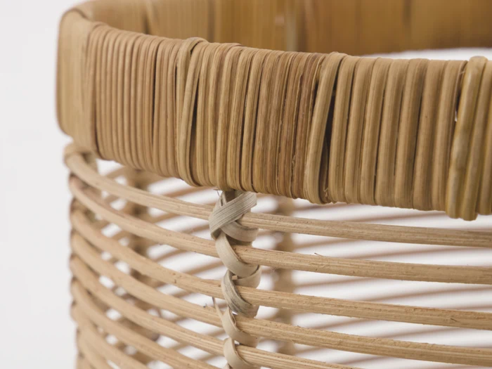 Nærbillede af en flettet kurv med lysebrune, afrundede og tæt sammenflettede strimler, der viser detaljeret tekstur og håndværk.