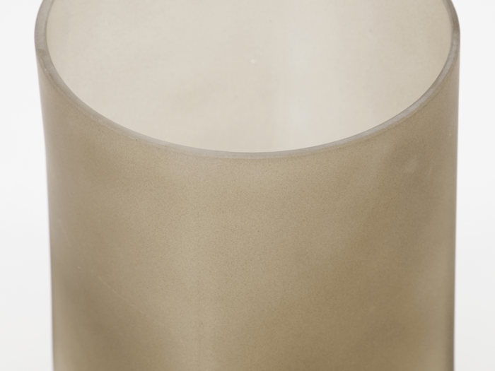 Nærbillede af en gennemskinnelig, beige cylinderformet genstand med en glat overflade, muligvis en glas- eller plastbeholder, på en hvid baggrund.