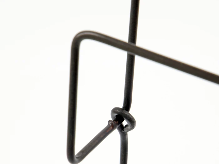 Nærbillede af krydsende sorte metalstænger med en bøjet samling mod en hvid baggrund.