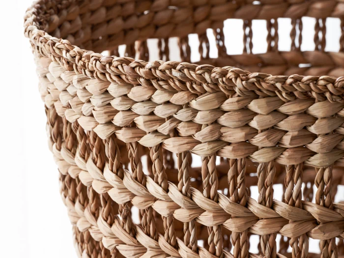 Nærbillede af en flettet kurv med naturligt lys, der skinner gennem det åbne, flettede mønster.