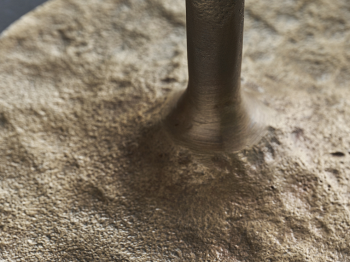 Nærbillede af en metalstang, der er fastgjort til en struktureret, ru, cirkulær guldbase.