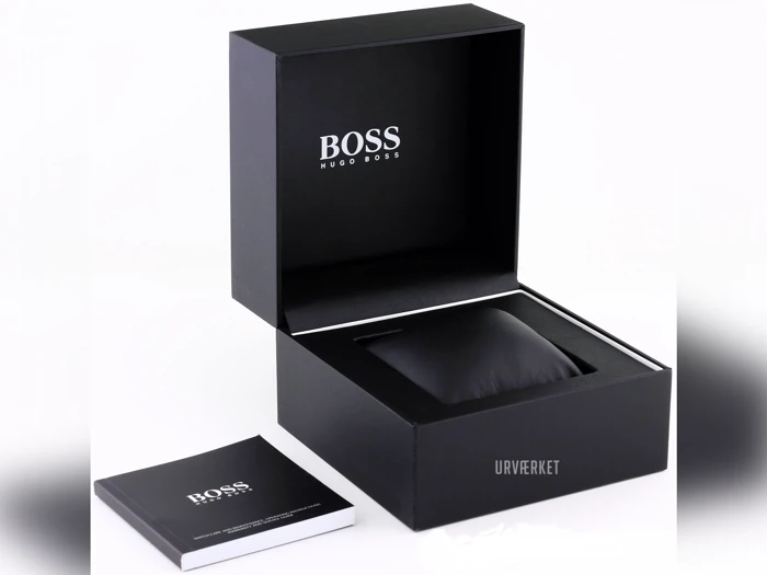 En sort Hugo Boss-urkasse med åbent låg, der viser et polstret rum indeni og et hæfte med påskriften BOSS placeret ved siden af.