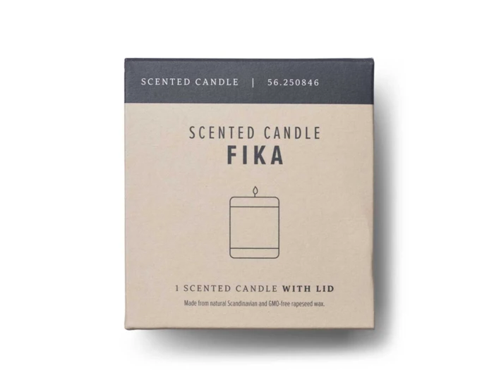 En æske mærket "Scented Candle FIKA" med en enkel lysillustration og en tekst, der angiver, at det er lavet af skandinavisk og GMO-fri rapsvoks.