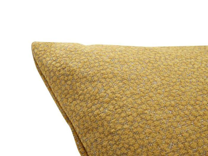 Et nærbillede af hjørnet af en sennepsgul stofpude med struktur på en hvid baggrund.