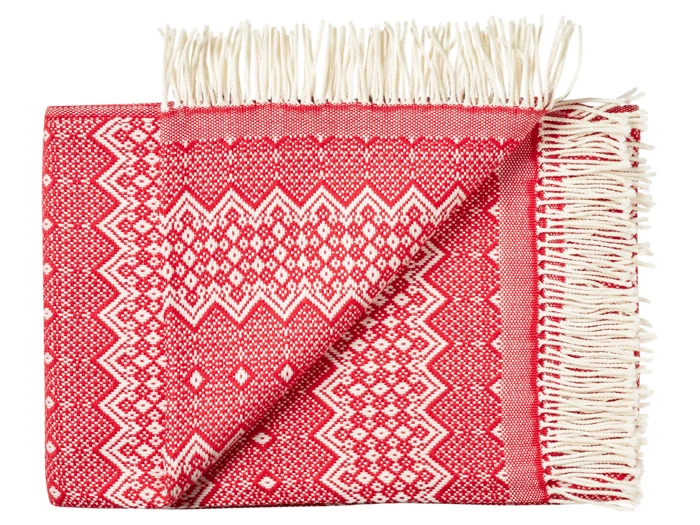 Et foldet rødt og hvidt vævet tæppe med geometriske mønstre og hvide frynser på den ene kant.