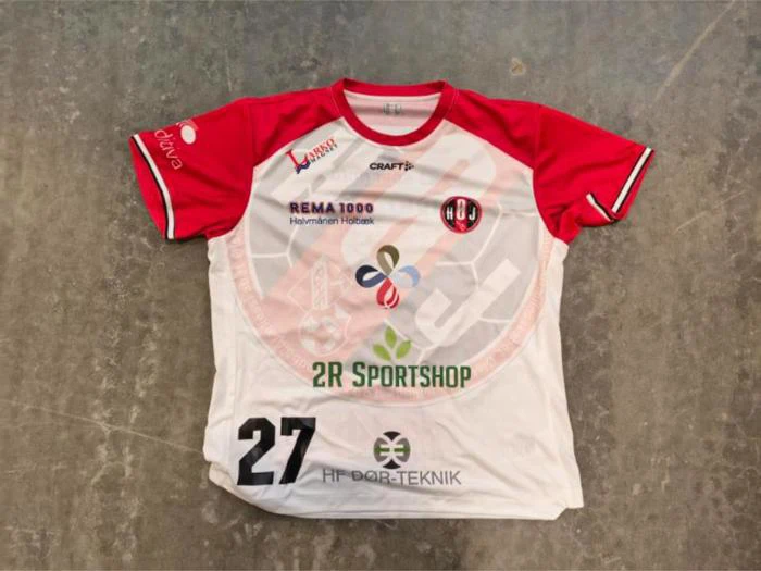 En rød og hvid sportstrøje med nummer 27 og forskellige sponsorlogoer, herunder Rema 1000 og 2R Sportshop.