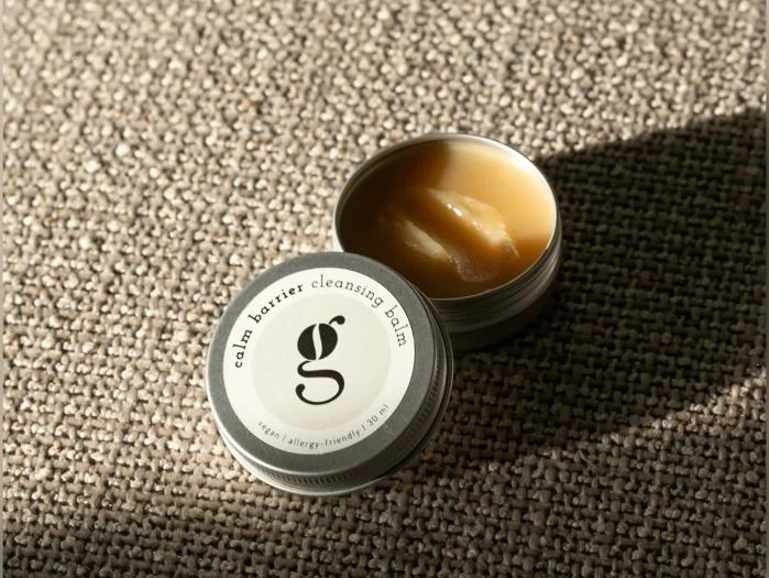 Åben dåse med Calm Barrier-rensende balsam med en cirkulær etiket med bogstavet g og teksten vegan | allergivenlig | 30 ml.