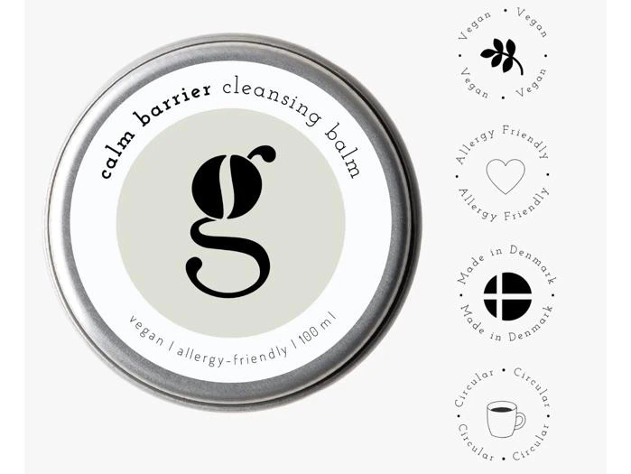En metalbeholder med Calm Barrier Cleansing Balm, ledsaget af symboler, der angiver, at produktet er vegansk, allergivenligt, fremstillet i Danmark og cirkulært.