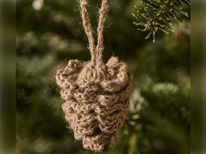 En julepynt i form af et fyrretræskogler, lavet af sammenrullet jutegarn, der hænger på en gren.
