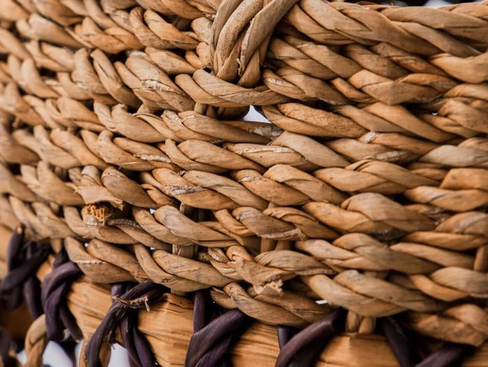 Nærbillede af en flettet kurv, der viser tæt sammenflettede naturfibre i lyse og mørkebrune nuancer.