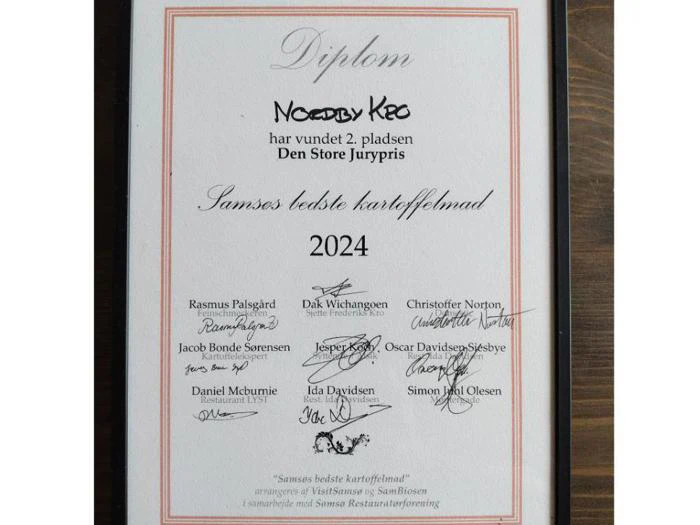 Et indrammet dansk diplom med underskrifter, der tildeler Nordby Kro 2. pladsen i konkurrencen Samsøs Bedste Kartoffelret 2024.