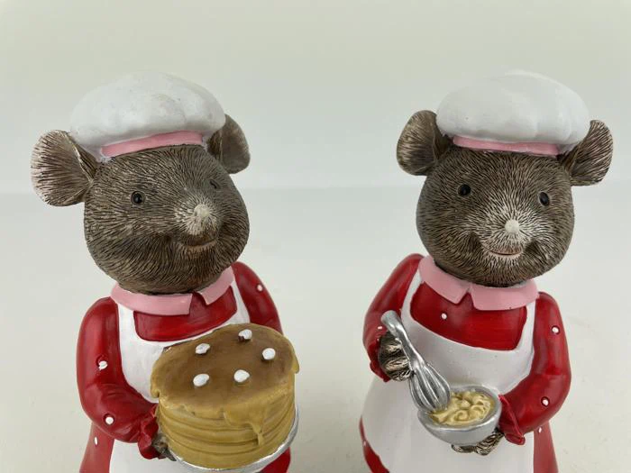 To keramiske musefigurer klædt ud som kokke; den ene holder en kage med hvide prikker, den anden holder en skål og et piskeris. Begge har rødt tøj på med hvide forklæder og kokkehuer.