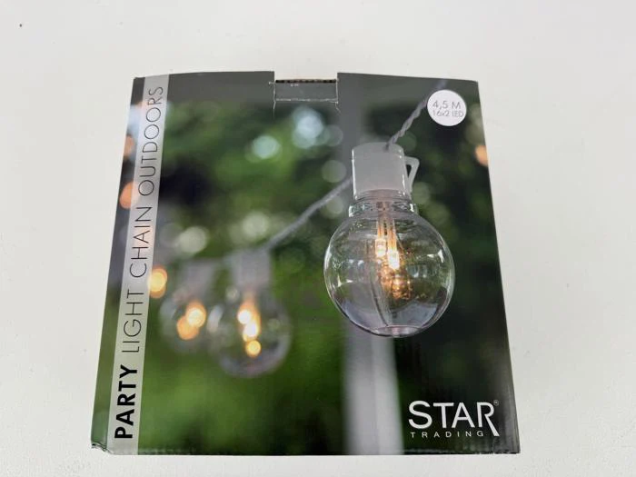 En æske STAR Trading festlyskæder til udendørs brug, der viser et nærbillede af runde pærelys med varm glød mod en sløret grøn baggrund.