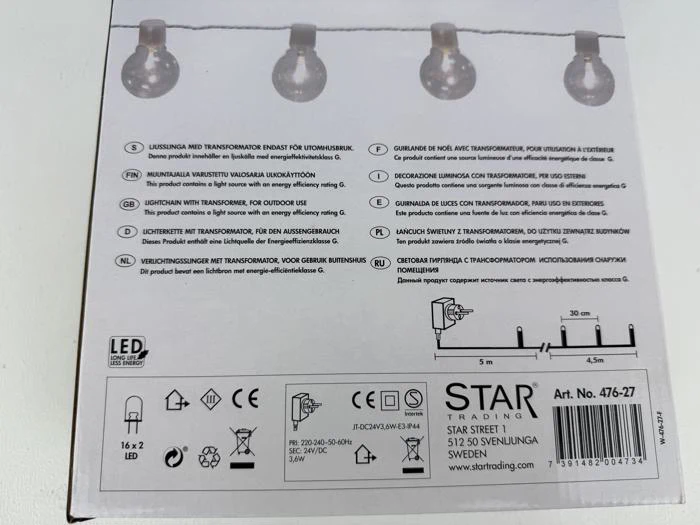 Æske til en lyskæde med pæreikoner, brugsanvisning på flere sprog, LED-label, tekniske specifikationer og Star Trading-branding i bunden.