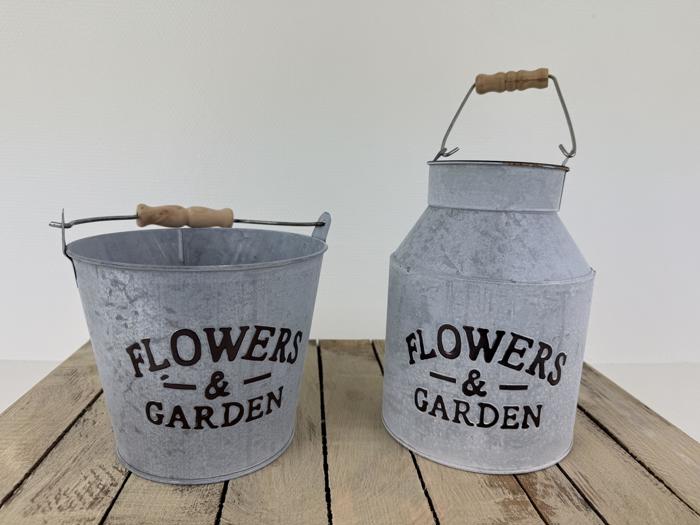 To metalbeholdere med træhåndtag mærket FLOWERS & GARDEN står på en træplade; den ene er en spand, og den anden er en dunk.