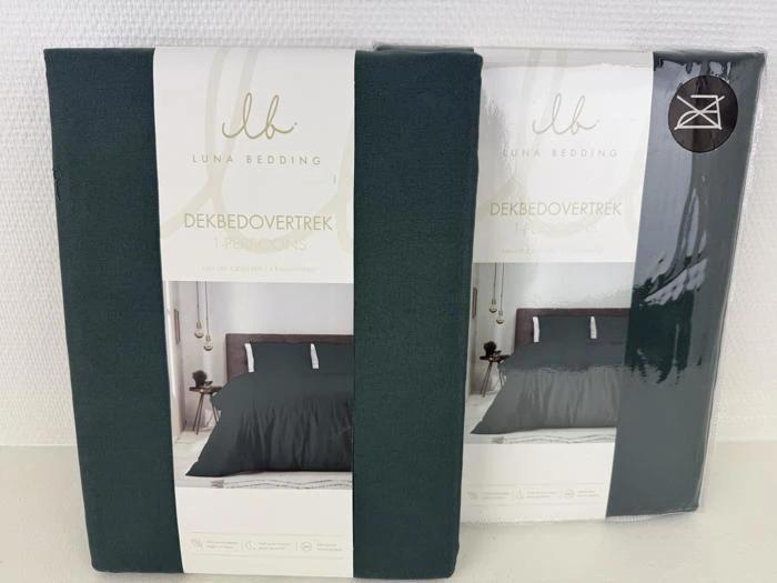 To pakkede, mørkegrønne enkeltsengesæt fra Luna Bedding står på højkant mod en hvid baggrund.