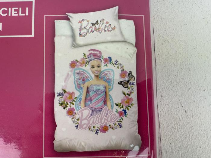 Et sæt med dynebetræk og pudebetræk i Barbie-fe-design med pink og lilla farver, blomster, en sommerfugl og ordet Barbie i dekorativ skrift.