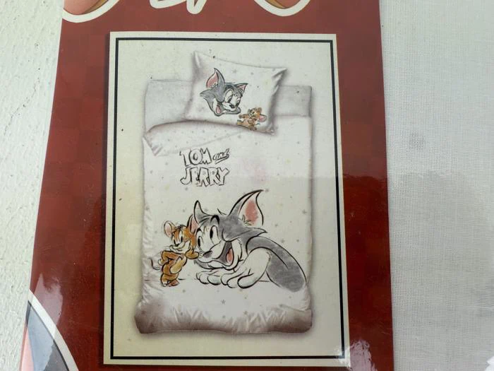 Et sengesæt med Tom og Jerry, hvor begge figurer er trykt på puden og dynen sammen med Tom og Jerry-logoet.