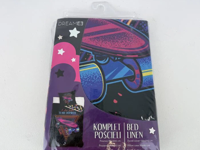 Et pakket sæt sengelinned med et farverigt design i retrostil med en person med solbriller og hat. På emballagen står der Dreamee og Komplet Pościeli | Bed Linen.