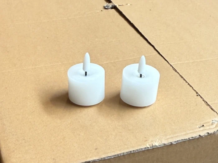 To små hvide LED-stearinlys med spidse toppe er placeret side om side på en almindelig brun papoverflade.