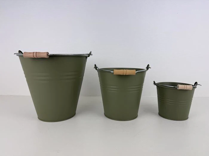 Tre grønne metalspande i forskellige størrelser med træhåndtag er anbragt i en række på en hvid flade mod en hvid baggrund.