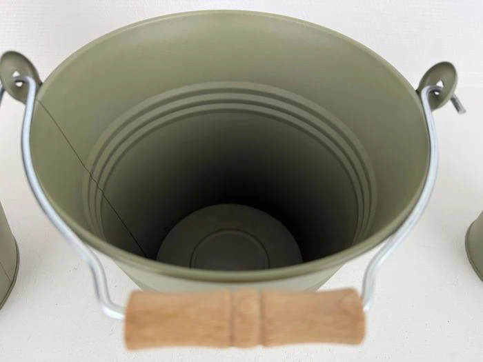 En grøn metalspand med træhank, set ovenfra, viser dens tomme indre.
