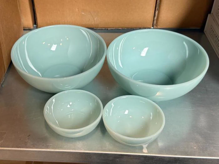 To store og to små lysegrønne glasskåle, der står på en metalhylde.