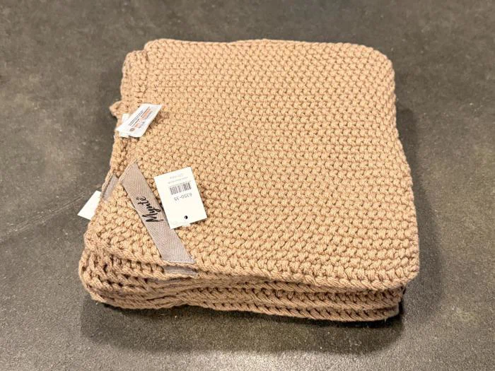 En stak foldede beige strikkede klude med et Mynte-mærke og en stregkodeetiket fastgjort.