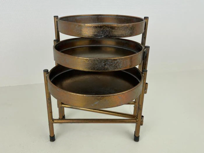 Et tredelt rundt metalstativ med en rustik bronzefinish med tre runde bakker stablet lodret på en metalramme.
