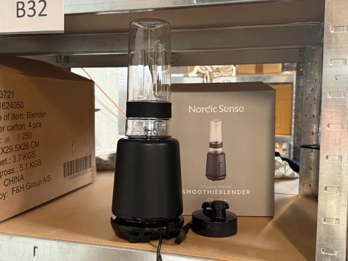 En Nordic Sense-smoothieblender står på en hylde ved siden af sin æske, og foran den ligger en afmonteret knivsenhed.