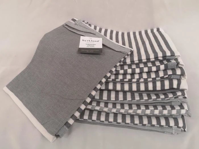 En stak foldede grå- og hvidstribede stofservietter med en serviet lagt ovenpå med et Hygihome-mærke.