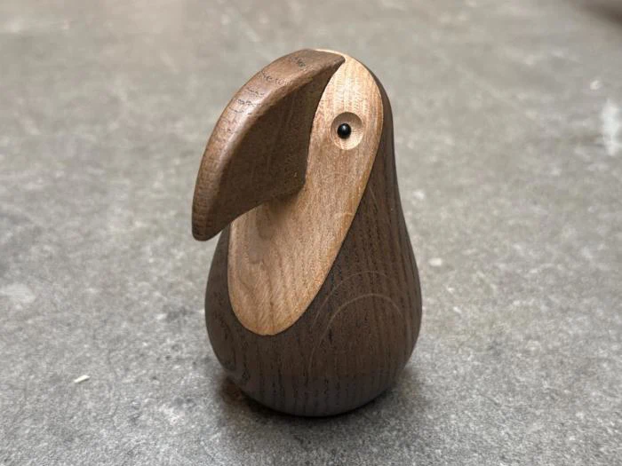 En lille, stiliseret fuglefigur af træ med et stort, buet næb.