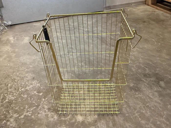 En kurv af guldtråd med en forsænket frontplade og håndtagskroge på siderne.