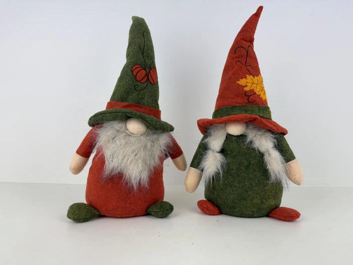 To nissedukker i plys med langt hvidt skæg, spidse hatte og ansigter med kun næse sidder side om side; den ene er iført rød og grøn hat, den anden er iført grøn og rød hat.