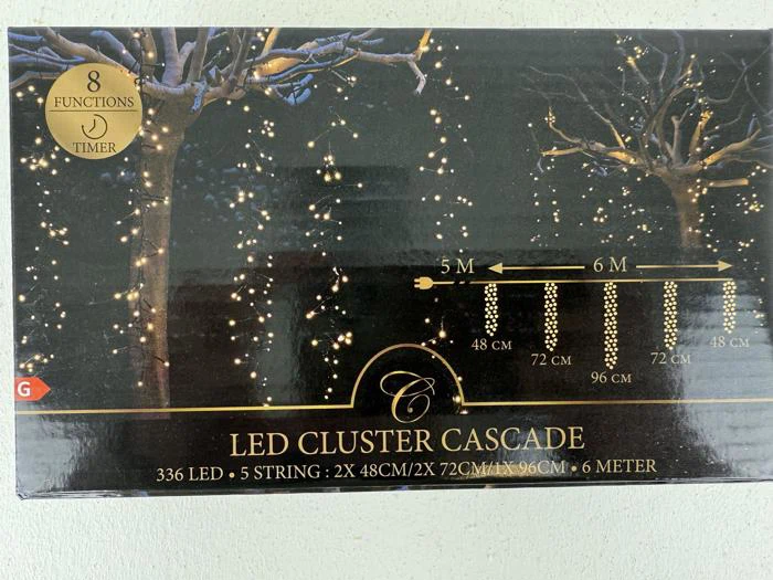 Æske med LED Cluster Cascade-lys med 336 LED'er, 5 strenge i forskellige længder, timer, 8 funktioner og en illustration af lys, der hænger på træer mod en mørk baggrund.