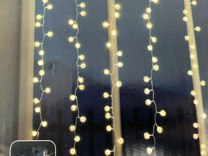 Strenge af varmhvide lyskugler hænger lodret foran en mørk baggrund og skaber en hyggelig, oplyst effekt.