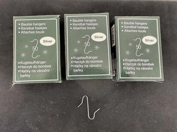 Der vises tre kasser med sølvkugleophæng, hver mærket med "50 Silver", med et ophæng liggende mellem to ubrugte ophæng foran kasserne.