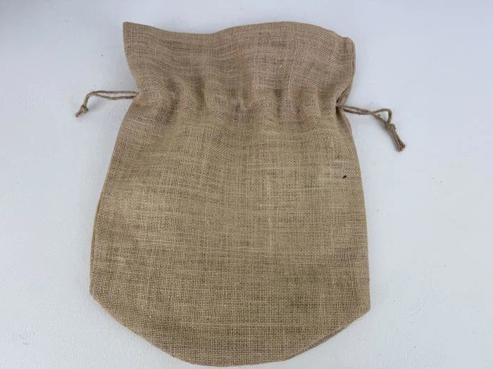 En brun jutepose med snor ligger fladt på en hvid overflade med synlige snore på begge sider nær toppen.