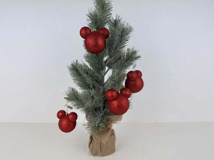 Lille kunstigt juletræ i jutebund, pyntet med fire røde glitterornamenter formet som Mickey Mouse-hoveder.