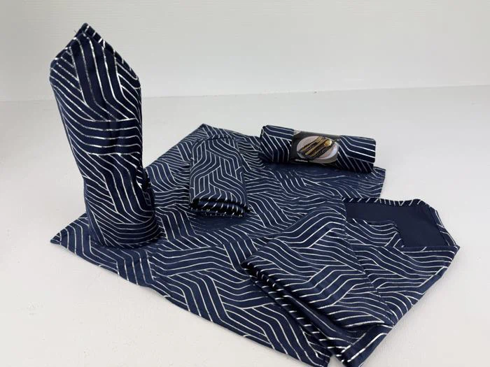 En borddækning med en blå- og hvidstribet serviet foldet i forskellige former, bl.a. en stående vifte, ruller og et rektangel på en matchende dækkeserviet.