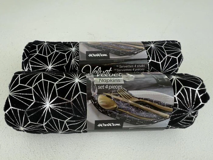 To rullede pakker med sorte fløjlsservietter med et hvidt geometrisk stjernemønster, hver mærket "Velvet Napkins set 4 pieces", vist med guldbestik på produktbilledet.