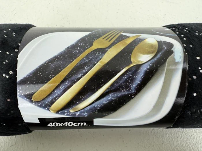En produktetiket viser guldfarvet bestik på en sort, stjernemønstret serviet placeret på en hvid tallerken. Der står 40x40 cm på etiketten.