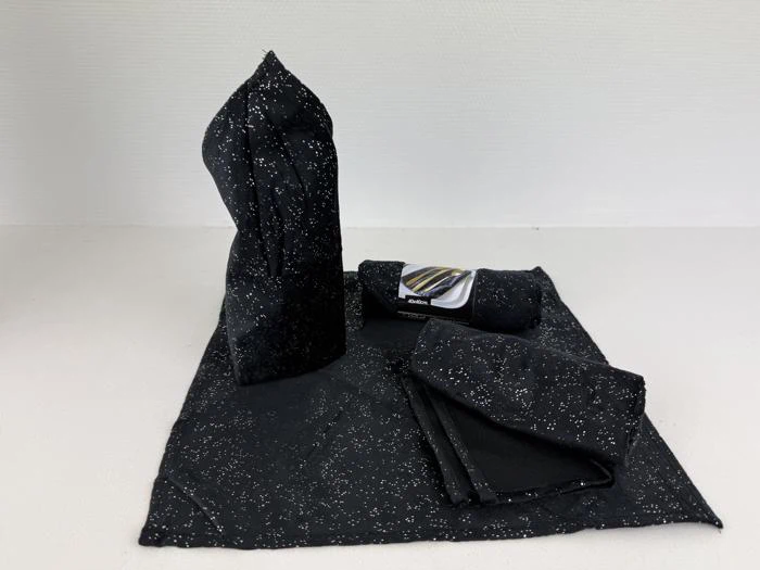 Et sort lommetørklæde med hvide pletter er foldet på tre forskellige måder og lagt ud på en hvid overflade mod en almindelig hvid baggrund.