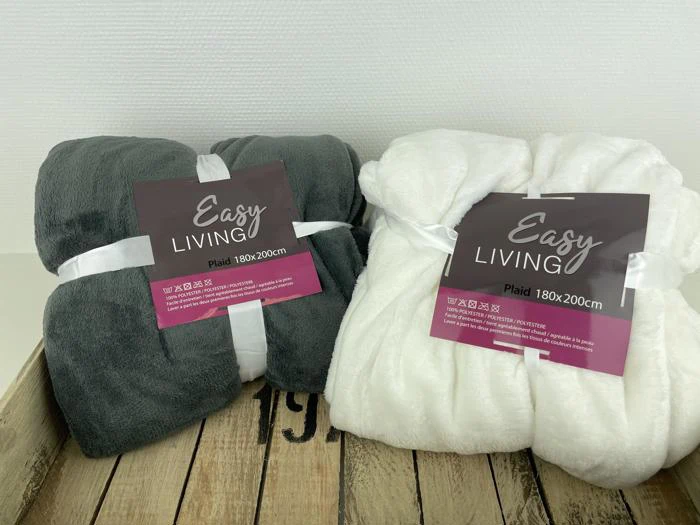 To fleecetæpper, et mørkegråt og et hvidt, hver med mærket Easy Living Plaid 180x200 cm, er udstillet på en træbakke mod en hvid baggrund.