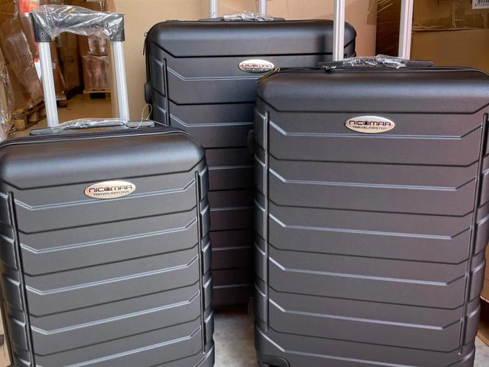 Tre sorte hardshell-kufferter i forskellige størrelser med teleskophåndtag, udstillet lodret og side om side indendørs.