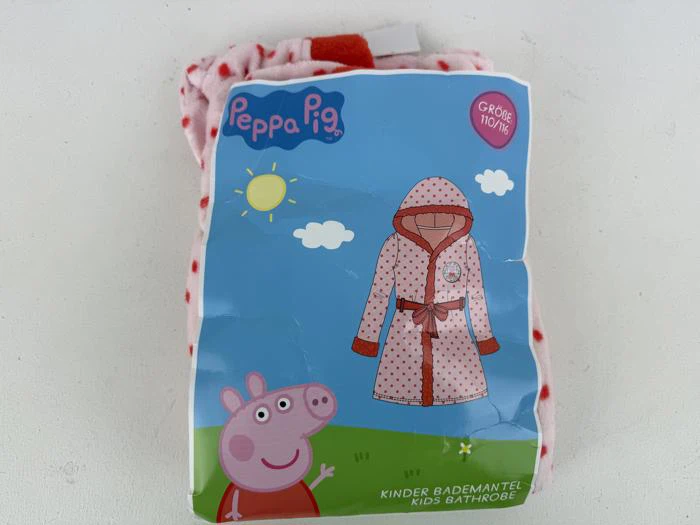 En badekåbepakke til børn med Peppa Pig-tema, der viser en illustration af Peppa Pig og en lyserød, prikket badekåbe på en solrig udendørs baggrund.